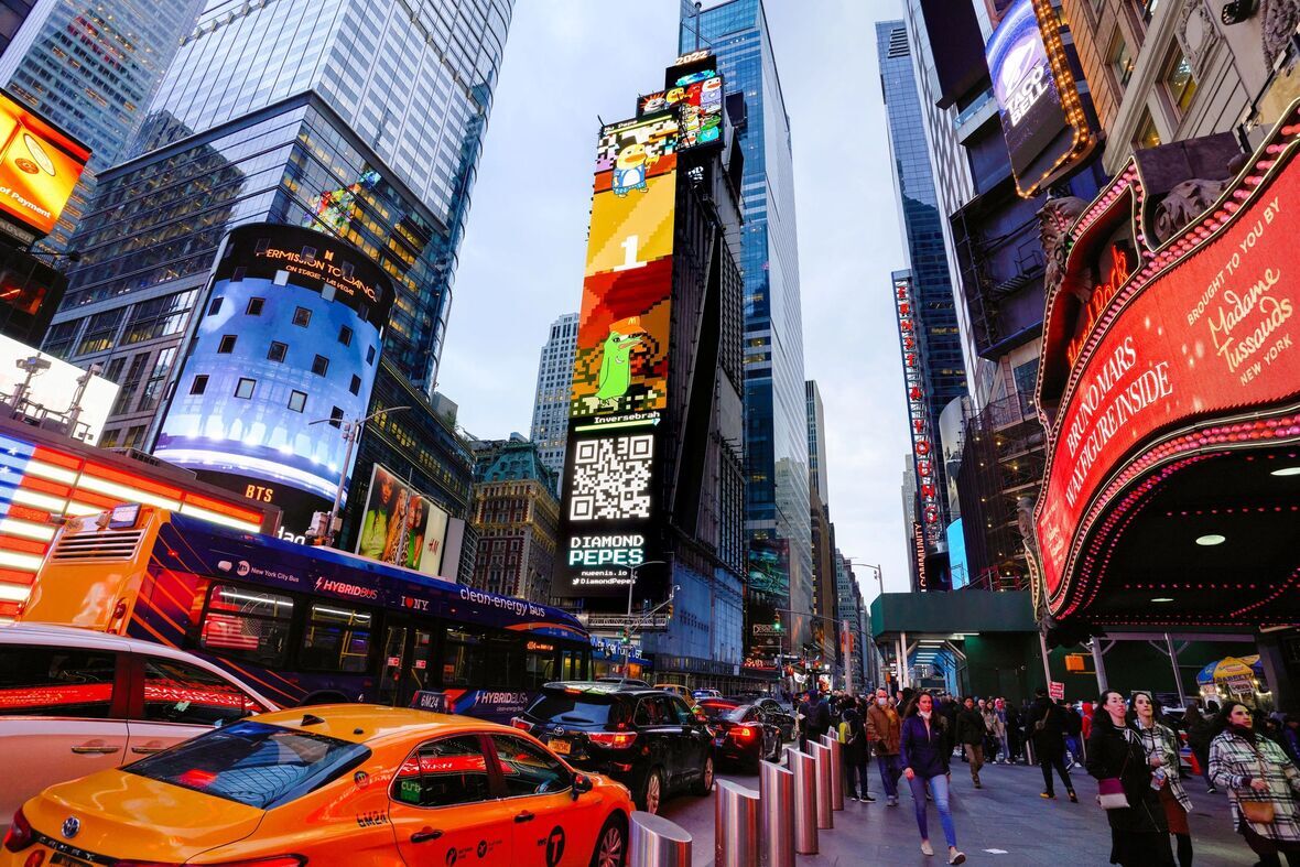 Billboard advertisement in Times Square featuring QR code and colorful graphics for Diamond Pepes, with busy street scene including yellow taxis and pedestrians.