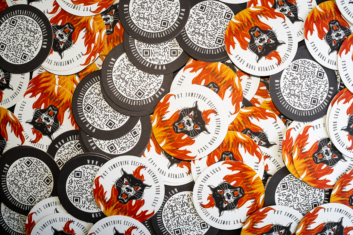 Circular coasters featuring a fierce black panther design surrounded by flames, with QR codes and text promoting American Traditional Rentals and their services.